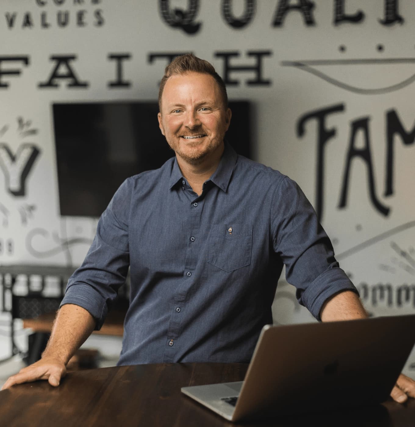 Jay Owen in the Business Builders office, with the agency's core values painted on the wall behind him.